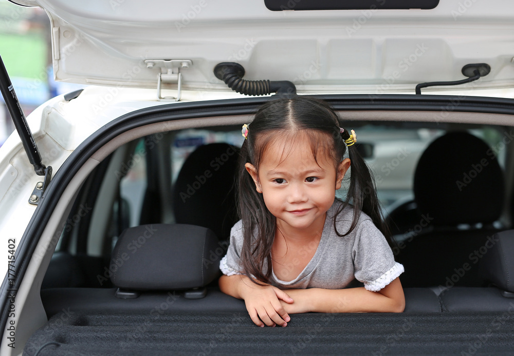 Smiling Asian child girl lying in the hatchback door of the car. Smiling Asian child girl lying in the hatchback door of the car.