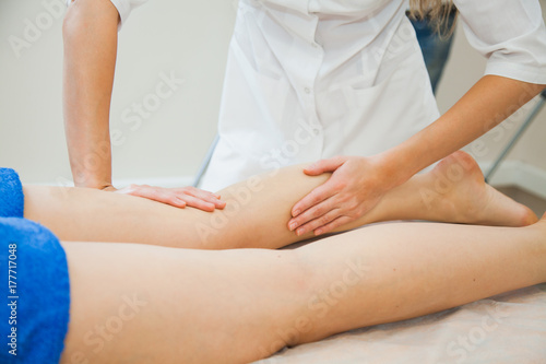 Young woman having massage at beauty spa salon. Beautician massaging female legs. Bodycare concept