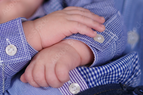 Newborn baby child close soft focus portrait of tiny tender skin hands and fingers wearing shirt