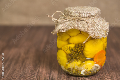 Patissony pickled in a glass jar on the table made of oak planks.Copyspace. photo