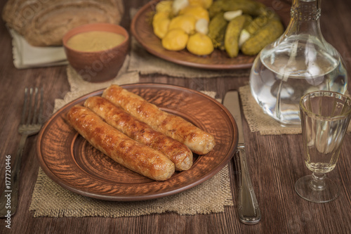 Grilled Bavarian sausages and salad with pickles and pickled patissonov of vodka. German food concept.