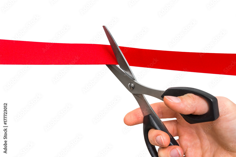Hand with scissors cutting red ribbon - opening ceremony Hand with scissors cutting red ribbon - opening ceremony