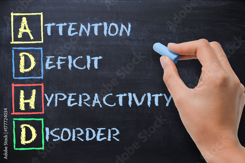 ADHD – attention deficit hyperactivity disorder handwritten by woman on blackboard photo