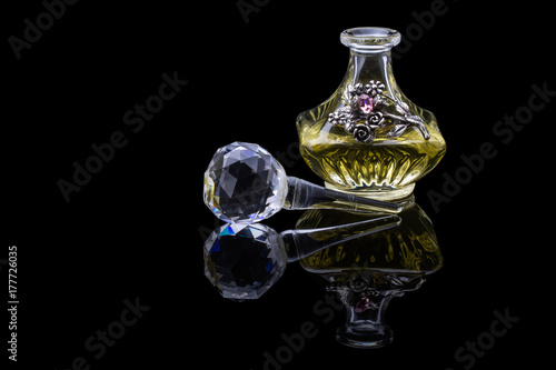 Close Up Shot Of Traditional Luxury Arabic Oud Oil Perfume In A Beautiful Handmade Clear Crystal Glass Jar Bottle and Glass Dropper Isolated On Black Background Antique Style, Text Space