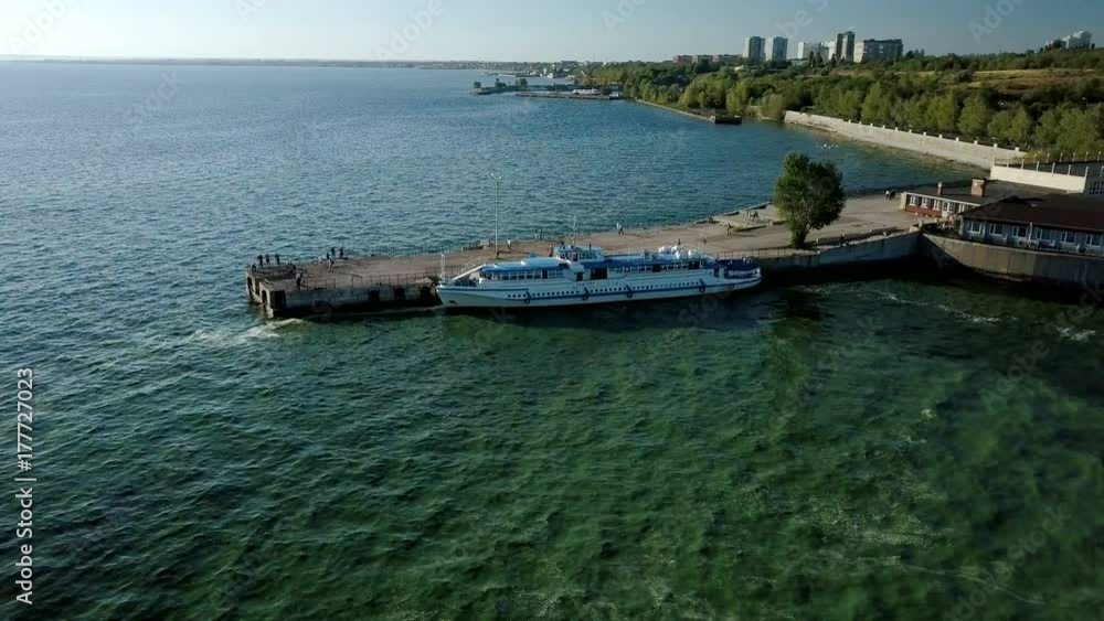 camera is flying around a long concrete pier with people and moored small river cruiser camera is flying around a long concrete pier with people and moored small river cruiser