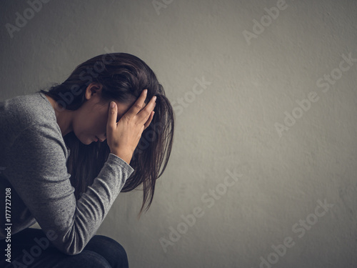 Depressed woman sitting on a chair in dark room at home. Lonly , sad, emotion concept. photo