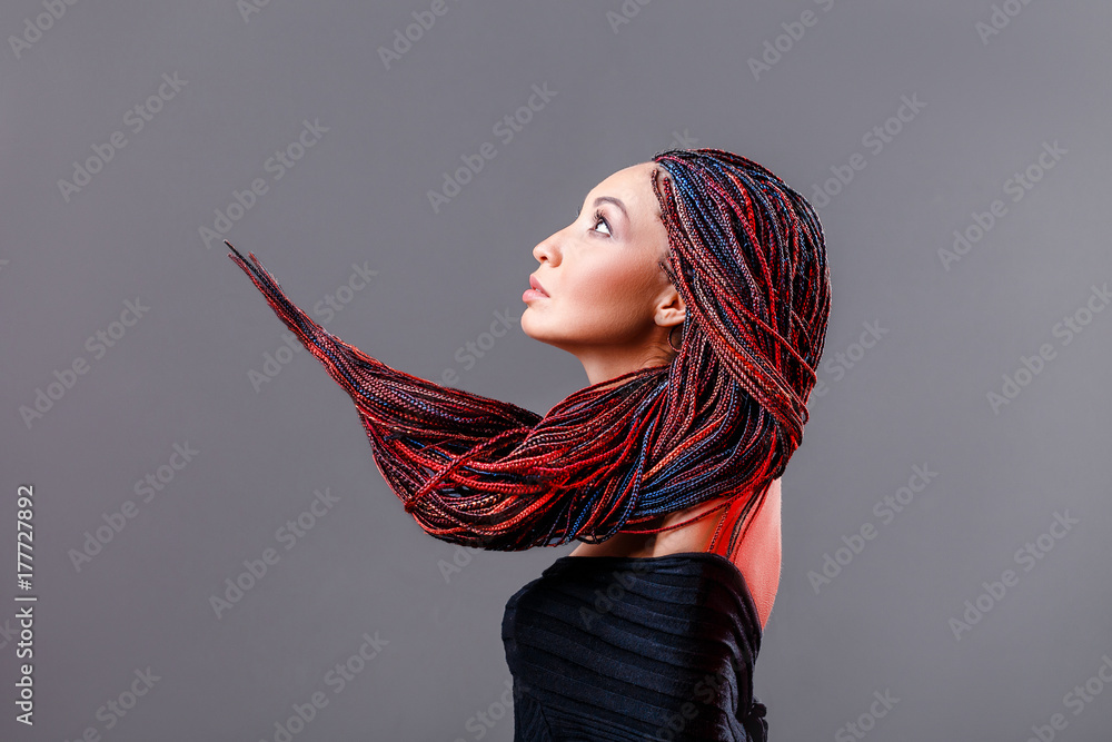 Photo Stock Fashion studio shoot of a mixed race woman with a creative  colorful hairstyle in the form of a pigtail braided from dreadlocks in the  technique of zizi. The concept of