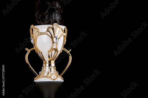White And Gold Arabic Traditional Incense Bukhoor Agar Wood Burner In A Mabkhara With Smoke Isolated On Black Background. Used In Majlis, Ramadan And Eid Occasions. Blank Text Space