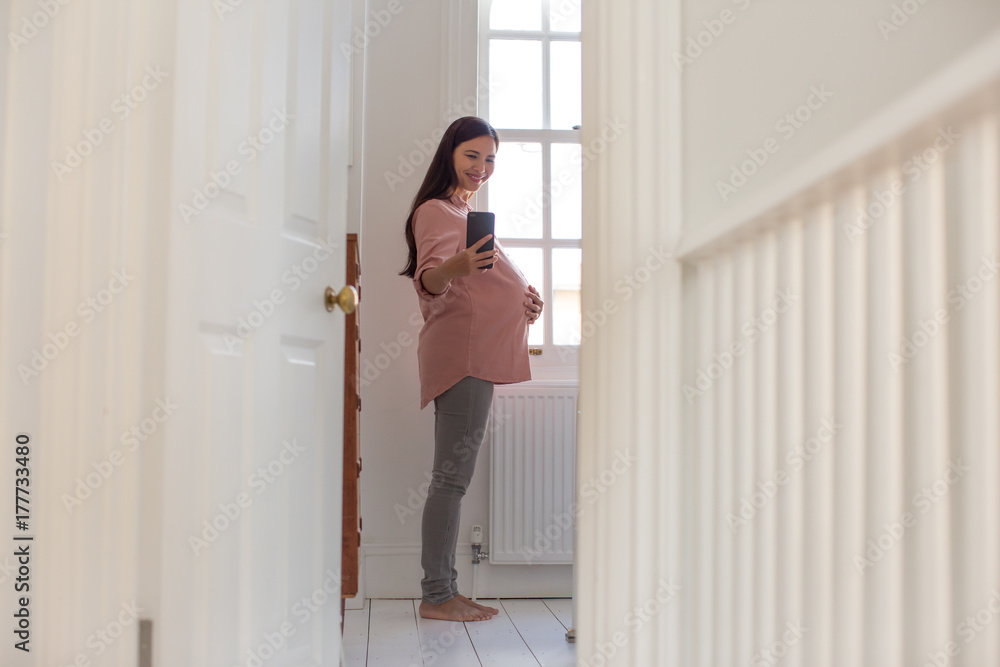 Pregnant woman taking selfie with smartphone