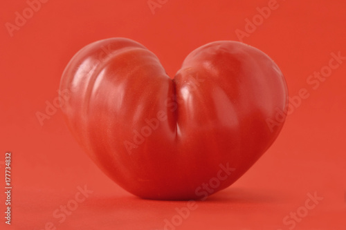 Heart shaped tomato on red background - Love concept © calypso77