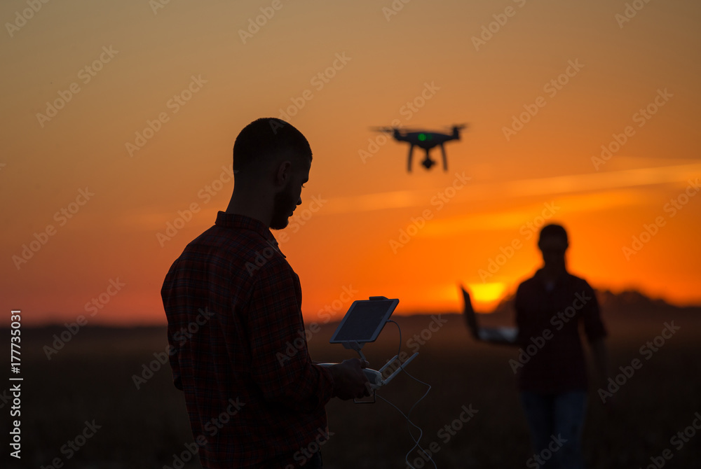 Man navigating drone above farmland - obrazy, fototapety, plakaty 