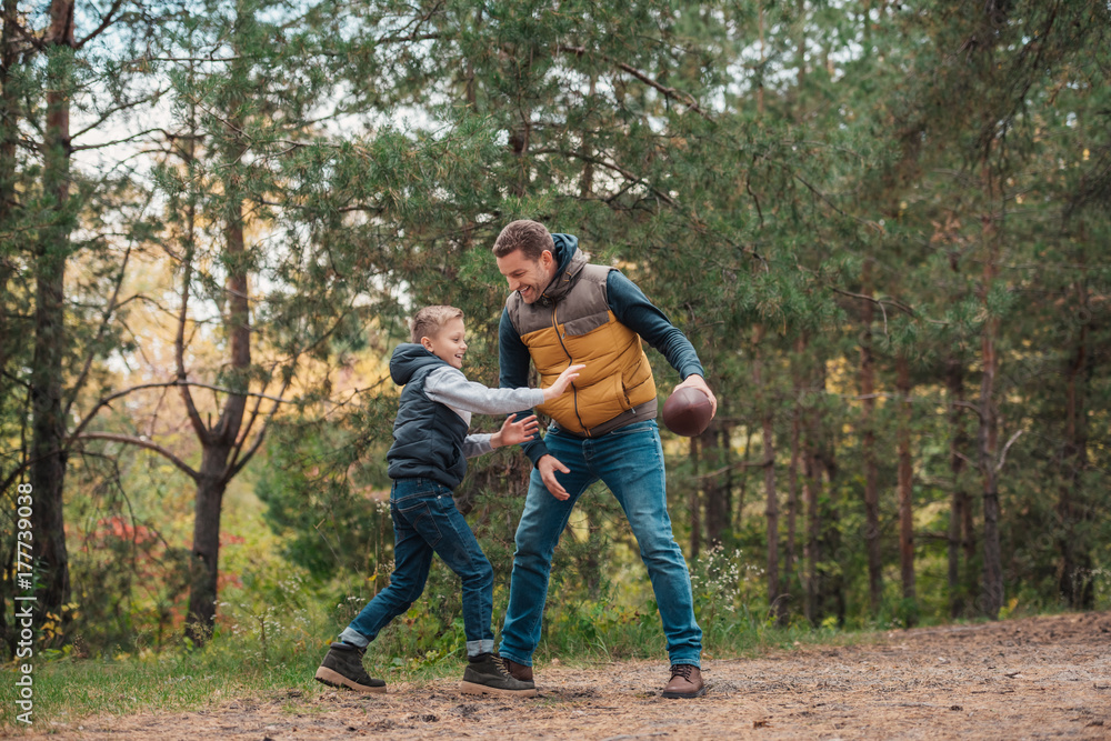 father and son playing with ball in forest