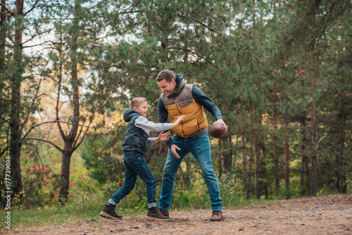 father and son playing with ball in forest