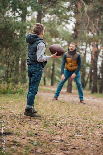 father and son playing with ball in forest