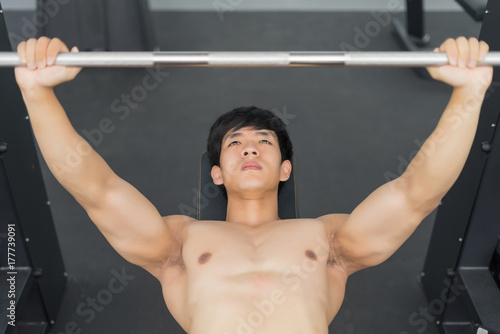 Fitness man in training showing exercises with barbells in gym
