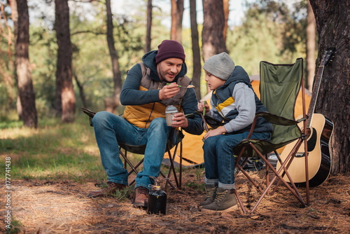 father and son eating in forest