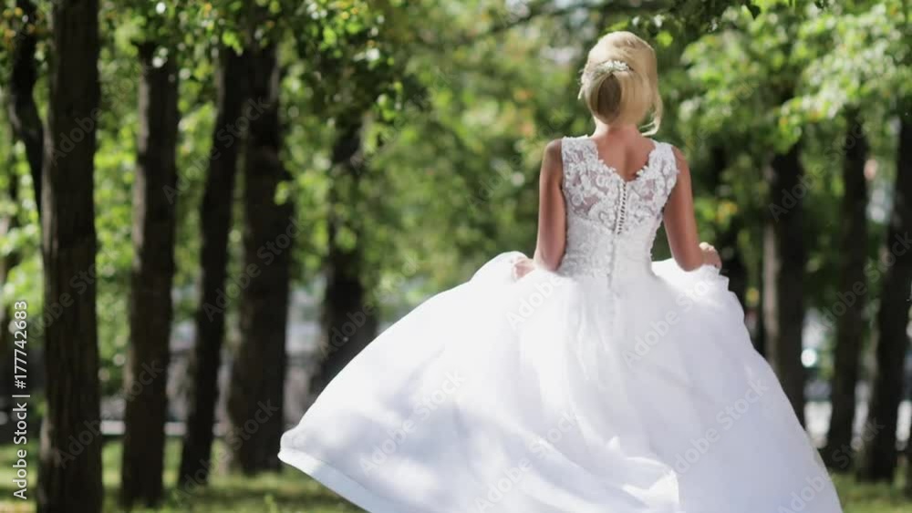 the bride dancing the park on her wedding day.The girl in a white dress with a train the bride dancing the park on her wedding day.The girl in a white dress with a train