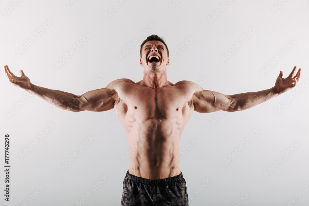 Obraz premium Screaming young sportsman standing with opened hands