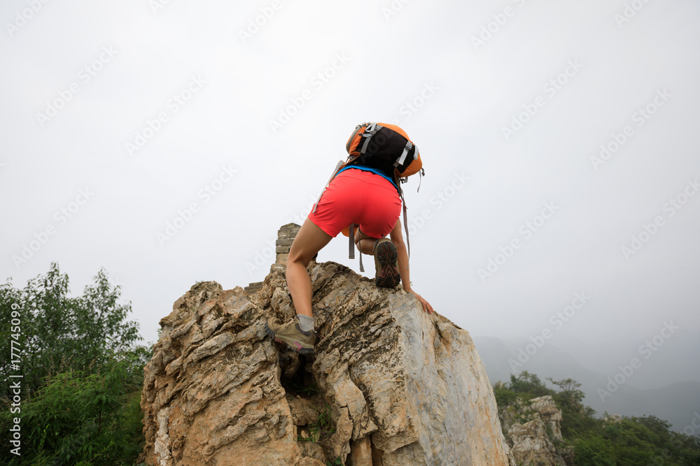 Fototapeta premium successful woman climber climbing rock on the top of mountain