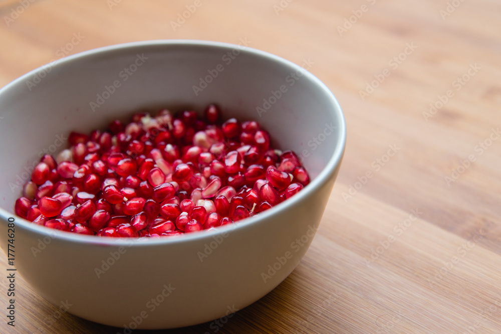 Grani melograno in una tazza su tavolo Grani melograno in una tazza su tavolo