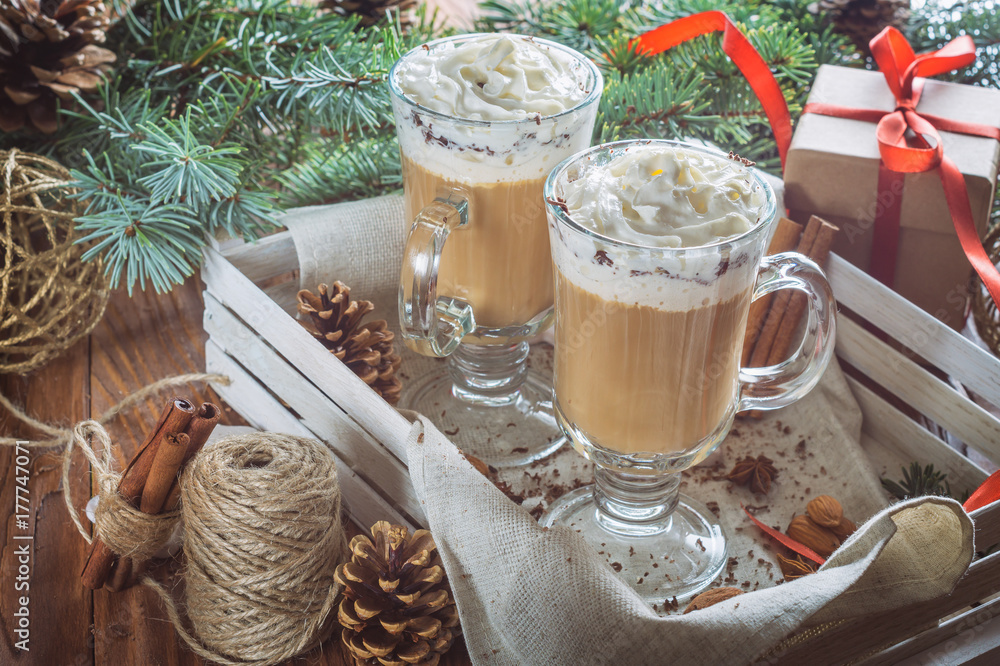 Christmas background with two latte, cookies star, fir branches, cones, gift and spices. Couple coffee with milk and homemade tasty cookies in tray on wooden background. Christmas background with two latte, cookies star, fir branches, cones, gift and spices. Couple coffee with milk and homemade tasty cookies in tray on wooden background.