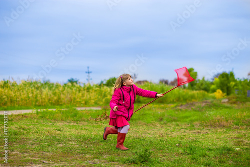 A little girl is running with butterfly net having fun on a fall day