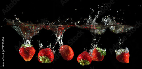 Strawberries splashing into water