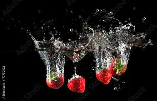 Strawberries splashing into water