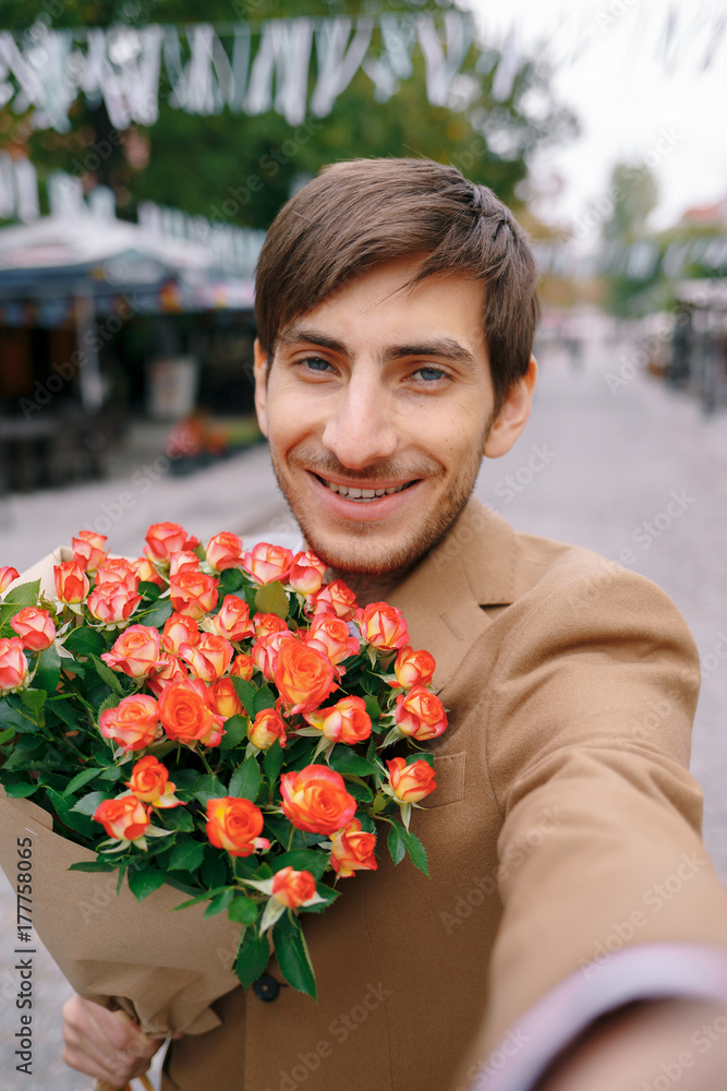 Fototapeta premium Uśmiechnięty mężczyzna Dokonywanie selfie z kwiatami