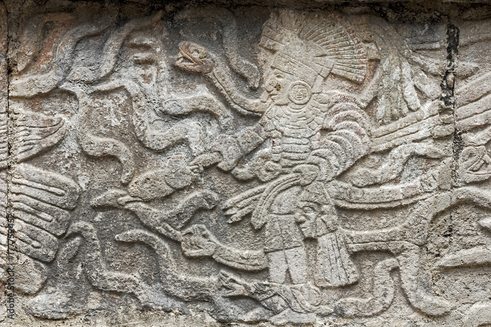Mayan stone carving in relief showing a king standing surrounded by snakes in Kabah, Mexico.