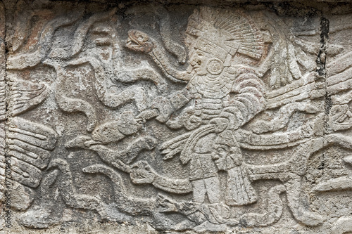 Mayan stone carving in relief showing a king standing surrounded by snakes in Kabah, Mexico.