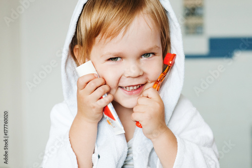 Portrait of a cute child with toothbrush and toothpaste in the bathroom.