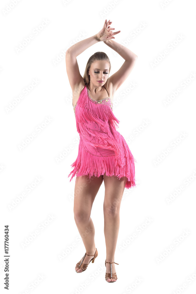Salsa latino female dancer in pink dress with arms raised looking down. Full body length portrait isolated on white studio background. 
