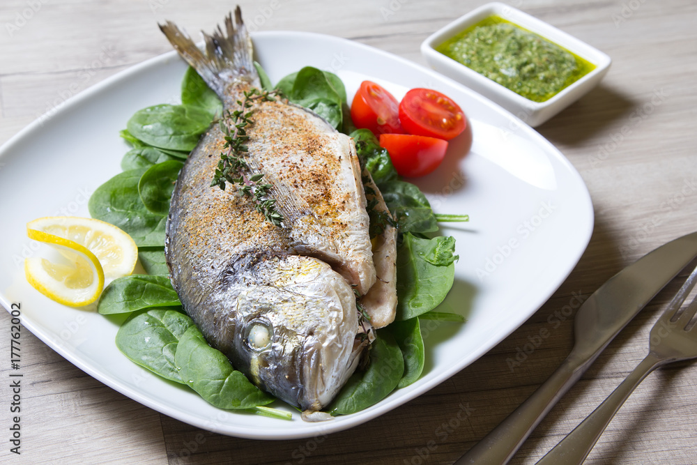 Baked Dorado with spinach and pesto sauce. Close-up. Selective focus. Baked Dorado with spinach and pesto sauce. Close-up. Selective focus.