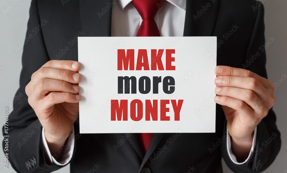 Businessman holding a card with text Make More Money Businessman holding a card with text Make More Money