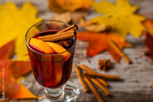 Hot Mulled Wine. On autumn background. Orange Cinnamon Red wine in the glass. Alcohol. Autumn leaves Yellow red. On wooden dark background.