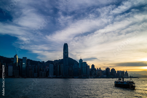 Hong Kong skyline cityscape and ferry traffic on Victoria harbor at twilight sunset