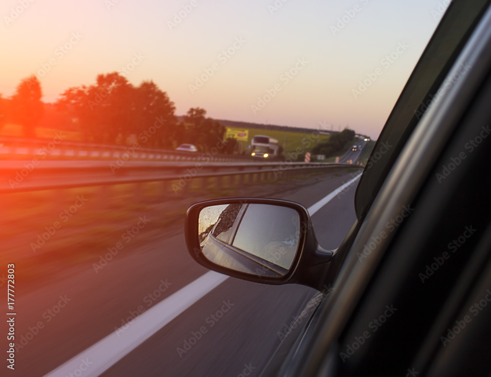 a long road lit by the sun and a machine, a visible white strip and trees a long road lit by the sun and a machine, a visible white strip and trees