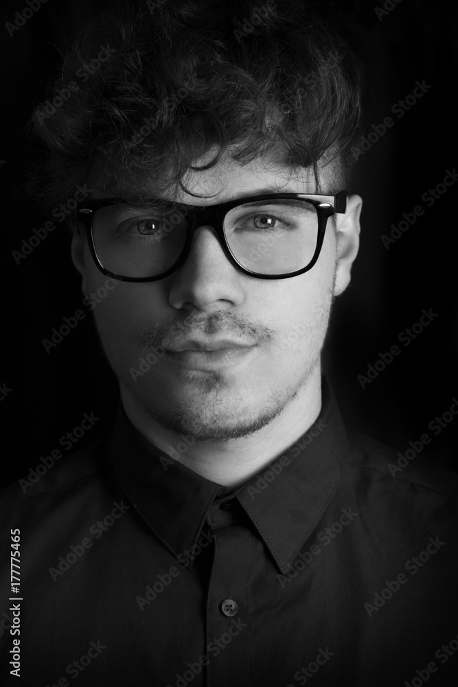 Black and white fashion dark portrait of sexy young with glasses on black background. of intelligent man. Photo portrait of curly fashion model with glasses with dark black background. Stock