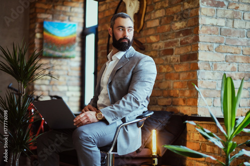 Stylish bearded male works with a laptop.