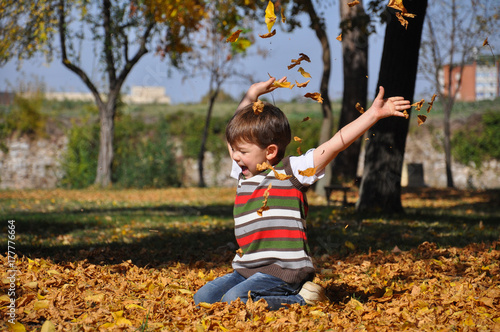 Boy throws leaves in autumn park . Boy play in park on a sunny October day