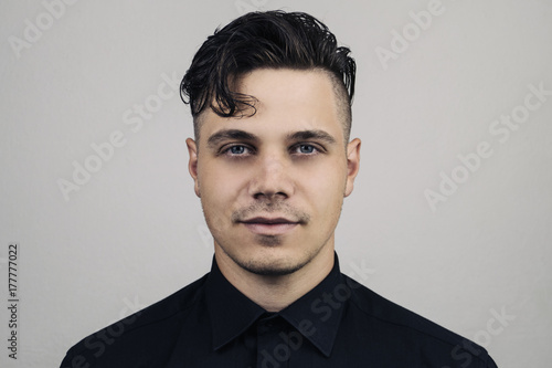 Tableau sur toile Portrait  of man in formal clothing (shirt) and perfect clean skin on grey background with studion light, Illuminated portrait of handsome male model with modern hairstyle