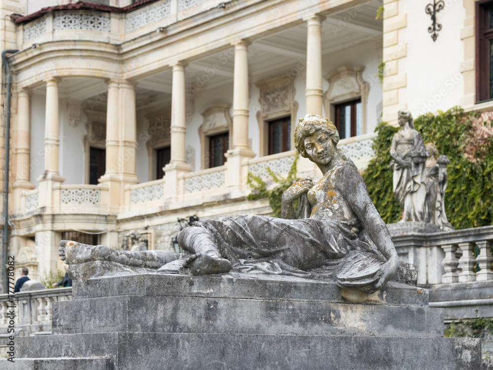 Naklejka premium Statue of a girl on a pedestal in the garden of the Peles castle in Sinaia, in Romania