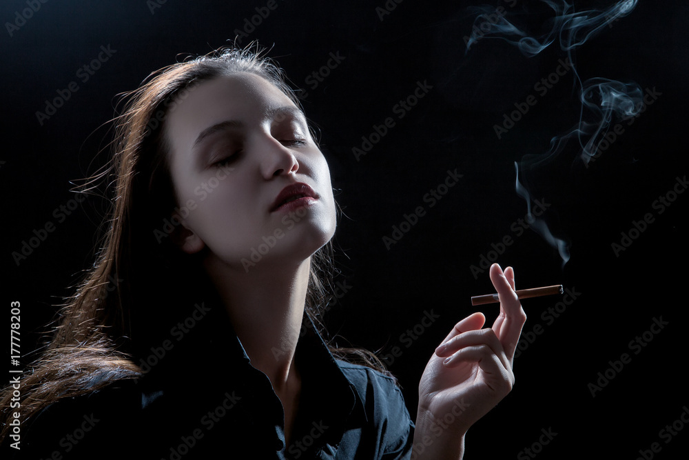 Fototapeta premium beautiful woman smoking cigarette on black background