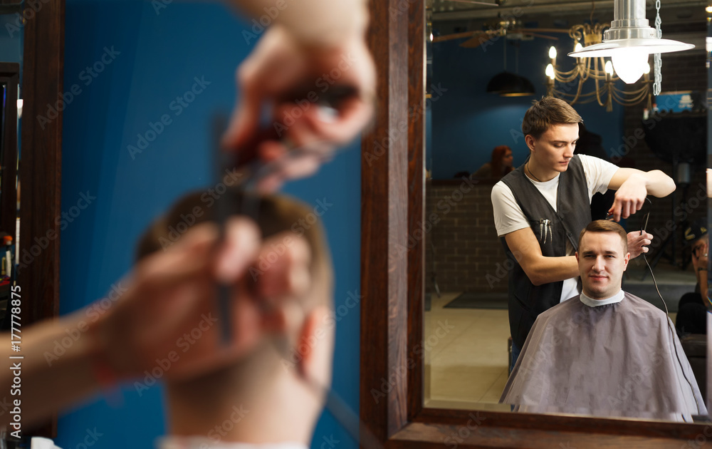 Fototapeta premium Man getting haircut by hairstylist at barbershop