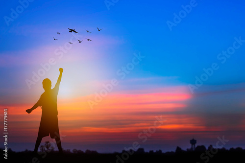 Fototapeta Naklejka Na Ścianę i Meble -  Success and winner concept, Silhouette of man standing and showing hand to celebrate in sunset and twilight..
