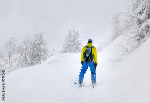 Man of back in ski touring under a snowfall