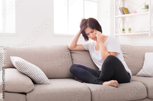 Young worried woman talking on cellphone