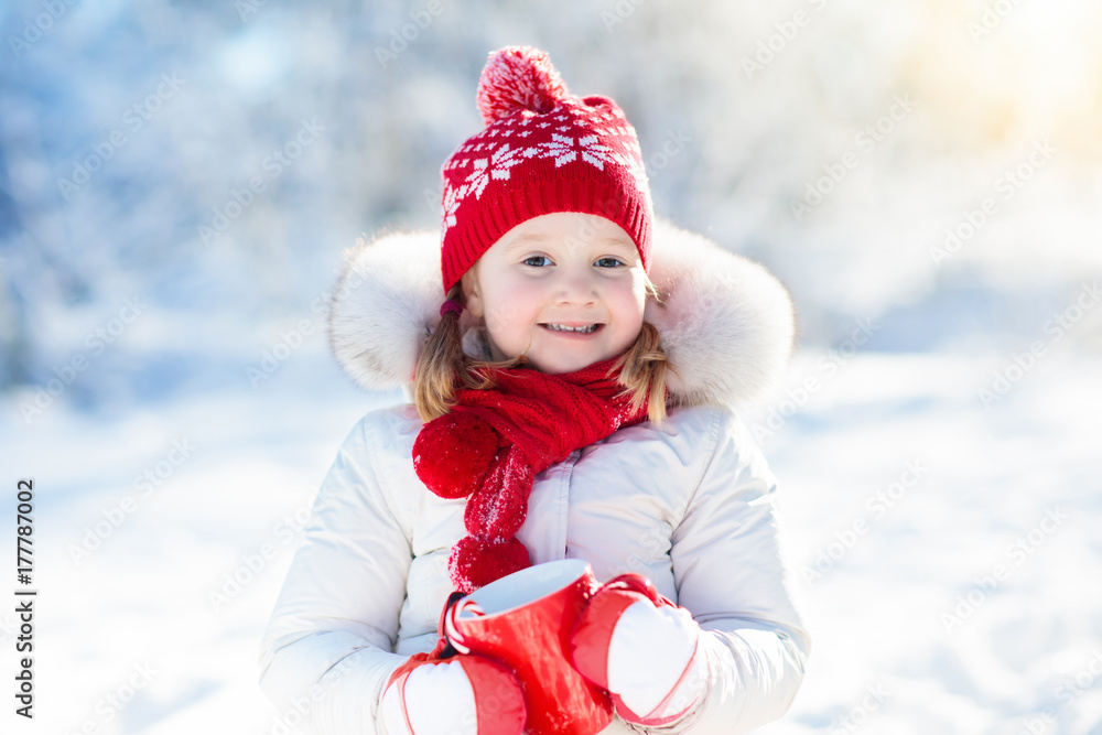 Child drinking hot chocolate in winter park. Kids in snow on Christmas. Child drinking hot chocolate in winter park. Kids in snow on Christmas.