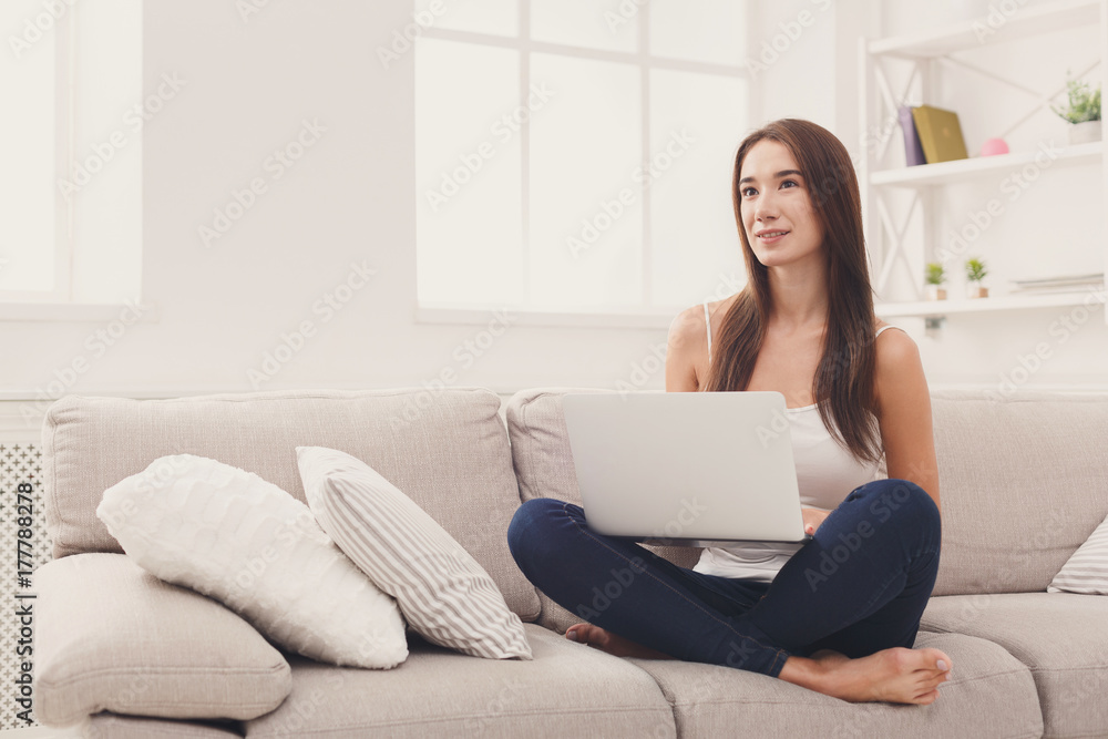Young girl with laptop sitting on beige couch Young girl with laptop sitting on beige couch